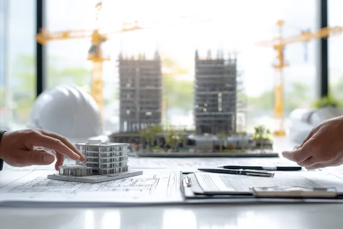 مدیران پروژه در حال بررسی مدل سه‌بعدی ساختمان و نقشه‌های اجرایی برای تهاتر زمین و واحدهای ساختمانی — تحلیل مالی و برنامه‌ریزی پروژه توسط گروه ساختمانی ساخَط